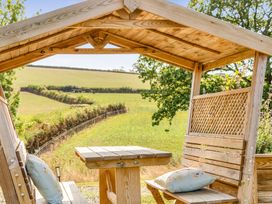 A wooden gazebo with a table and benches at Cosy Luxury Owls Roost Hut with Private Hot Tub near Little Deptford Farm near Umberleigh