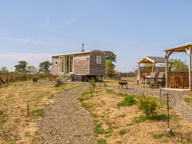 A wooden cabin and outdoor seating area at Cosy Luxury Owls Roost Hut with Private Hot Tub near Little Deptford Farm near Umberleigh