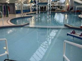 An indoor pool area with slides and lounge chairs at Charming Caravan in beautiful Seton Sands Cockenzie And Port Seton