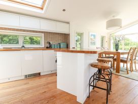 A kitchen with wooden bar stools and dining area at 4 Tree Tops Liskeard