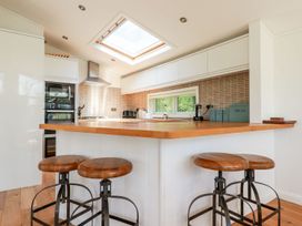 A kitchen with bar stools and appliances at 4 Tree Tops in Liskeard