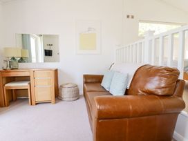 A living room with a sofa and a wooden chest of drawers at 4 Tree Tops in Liskeard