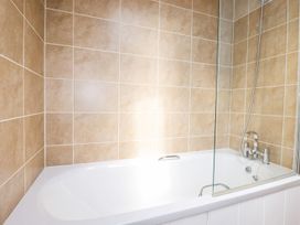 A bathtub with a shower screen and faucet at 4 Tree Tops in Liskeard