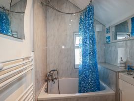 A bathroom with a bathtub and shower curtain at Harbourside Retreat in Looe