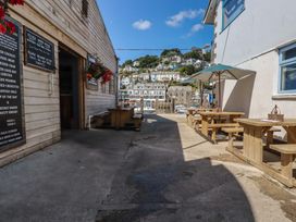 An outdoor dining area with wooden tables and umbrellas at Harbourside Retreat in Looe