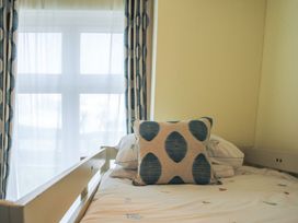 A bed with a pillow and curtains in a bedroom at 4 The Salcombe in Salcombe
