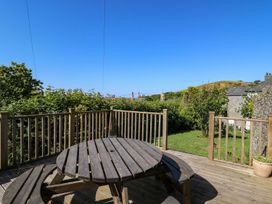 An outdoor area with a table overlooking a garden at Dewi Villa Apartment Aberaeron