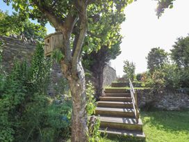 A garden with a tree, birdhouse, and wooden stairs at Dewi Villa Apartment Aberaeron