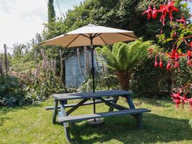 A picnic table with an umbrella and greenery at The Jingle House in Tregony