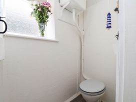 A bathroom with a toilet and a vase of flowers at the Farmhouse in Whitby