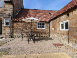 An outdoor area with a table and chairs under an umbrella at the Farmhouse in Whitby