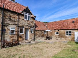 A garden with a table and chairs under an umbrella at Farmhouse Whitby