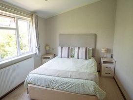 A bedroom with a bed, bedside table, and window at Oak Lodge