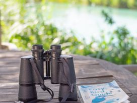 A pair of binoculars and a bird guide book on a table near a body of water at Oak Lodge 