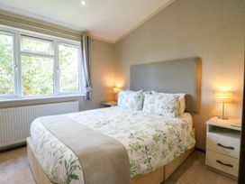 A bedroom with a bed and windows at Oak Lodge Battisford near Stowmarket