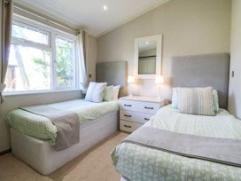 A bedroom with two beds and a chest of drawers at Oak Lodge Battisford near Stowmarket