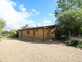 A wooden lodge with gravel driveway and trees at Cherry Lodge Battisford near Stowmarket