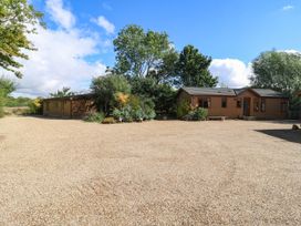 An outdoor area with two lodges surrounded by trees at Cherry Lodge Battisford near Stowmarket
