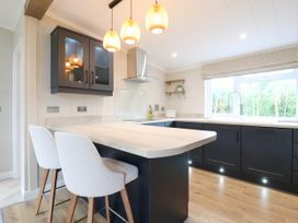 A kitchen with an island and bar stools at Cherry Lodge Battisford near Stowmarket