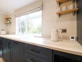 A kitchen with a sink, kettle, and window at Cherry Lodge Battisford near Stowmarket