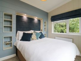 A bedroom with a bed and shelves at Cherry Lodge Battisford near Stowmarket