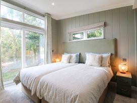 A bedroom with twin beds and large windows at Cherry Lodge, Battisford near Stowmarket