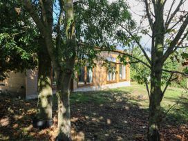 A wooden exterior structure surrounded by trees at Cherry Lodge Battisford near Stowmarket