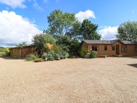 An outdoor area with two houses and greenery at Cherry Lodge Battisford near Stowmarket