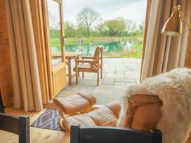 A living room with a view of a lake at Willow Lodge in Stowmarket