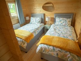A bedroom with two twin beds and a lamp between them at Willow Lodge in Stowmarket