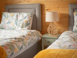 A bedroom with two beds and a lamp on a nightstand at Willow Lodge in Stowmarket