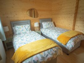 A bedroom with two beds and a mirror at Willow Lodge in Stowmarket