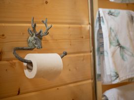 A bathroom with a toilet paper holder and towels at Willow Lodge Stowmarket