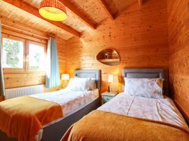 A bedroom with two beds and a mirror at Willow Lodge in Stowmarket