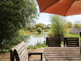 A garden view with a table and chairs overlooking a body of water at Willow Lodge Stowmarket
