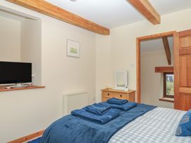 A bedroom with a bed and television at Brimble Cottage at Dockwell Farm Newton Abbot