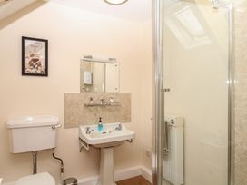 A bathroom with a toilet, sink, mirror, and shower at Brimble Cottage at Dockwell Farm Newton Abbot