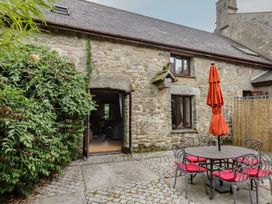 An outdoor seating area with a stone wall and table at Brimble Cottage at Dockwell Farm in Newton Abbot
