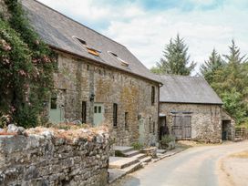 A stone building with flowers and trees at Brimble Cottage at Dockwell Farm in Newton Abbot