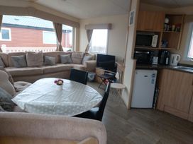 A living room with sofa and kitchen area at Golden Sands FSB38 Rhyl