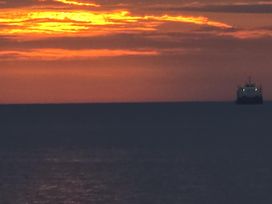 A sunset over the ocean with a ship on the horizon