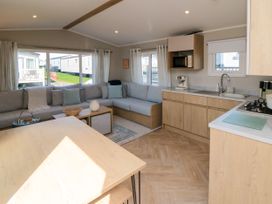 A living room with a sofa and kitchen area at 5 Rowen Court Scarborough