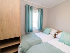 A bedroom with two beds and a wardrobe at 5 Rowen Court in Scarborough