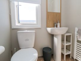 A bathroom with a toilet, sink, and mirror at 5 Rowen Court in Scarborough