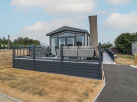 An outdoor area with a hot tub and grey sofa at Lodge 1 St. Osyth