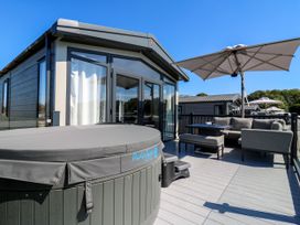 An outdoor seating area with a hot tub and umbrella at Lakewood Plot 1 St. Osyth