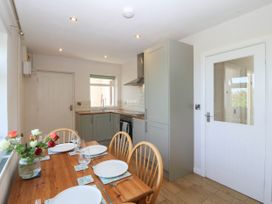 A kitchen with a dining table and chairs at Wilpol in Llanerchymedd