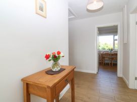 A hallway with a table and flowers at Wilpol in Llanerchymedd