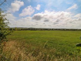 A field with grass and trees under a cloudy sky at Wilpol in Llanerchymedd