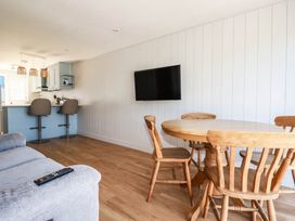 A dining room with a table and chairs and a television at 9 Tides Reach Wadebridge